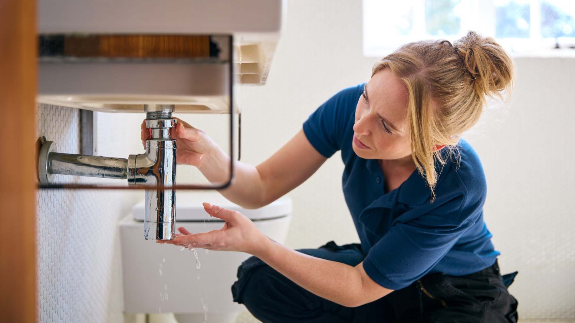 female-plumber-fixing-leak-in-domestic-bathroom-si-2024-10-19-07-40-49-utc